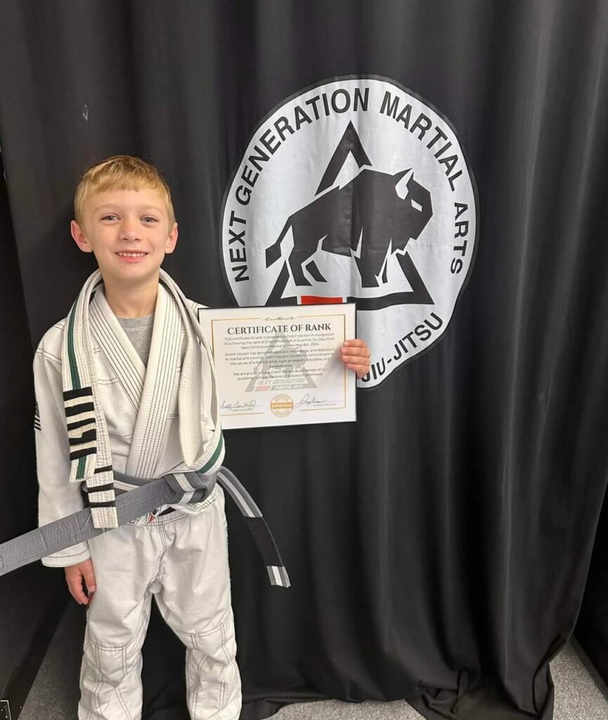 A child receiving a new belt after a martial arts promotion ceremony