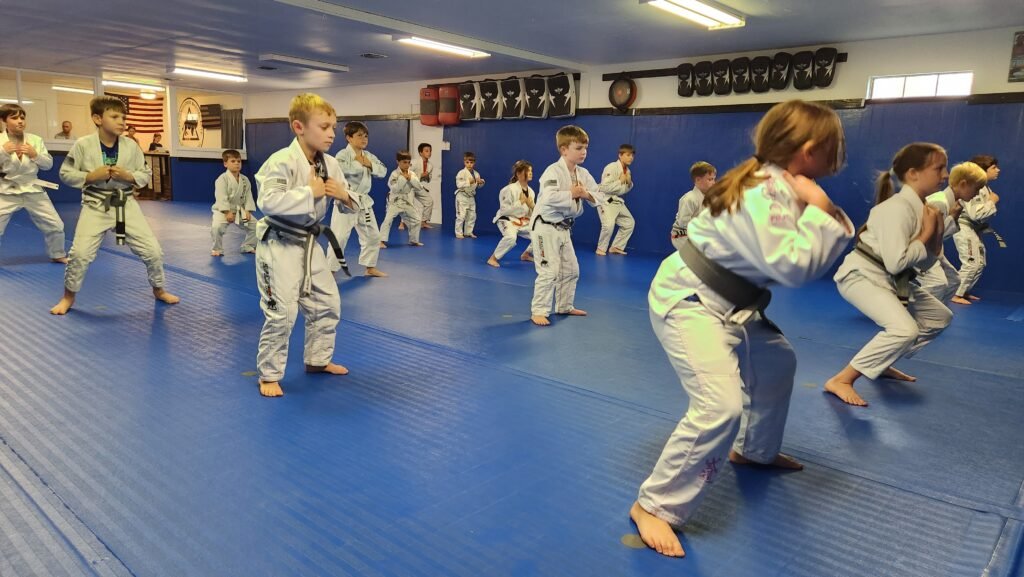 Child learning Brazilian Jiu Jitsu techniques to build confidence and develop self-defense skills.